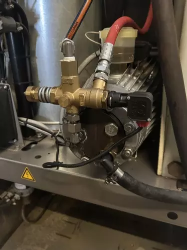 Internal view of a Nilfisk SH Truck Booster pump setup prior to installing an over-temperature protection system. The machine had previously suffered overheating issues due to continuous running caused by leaking trigger guns.